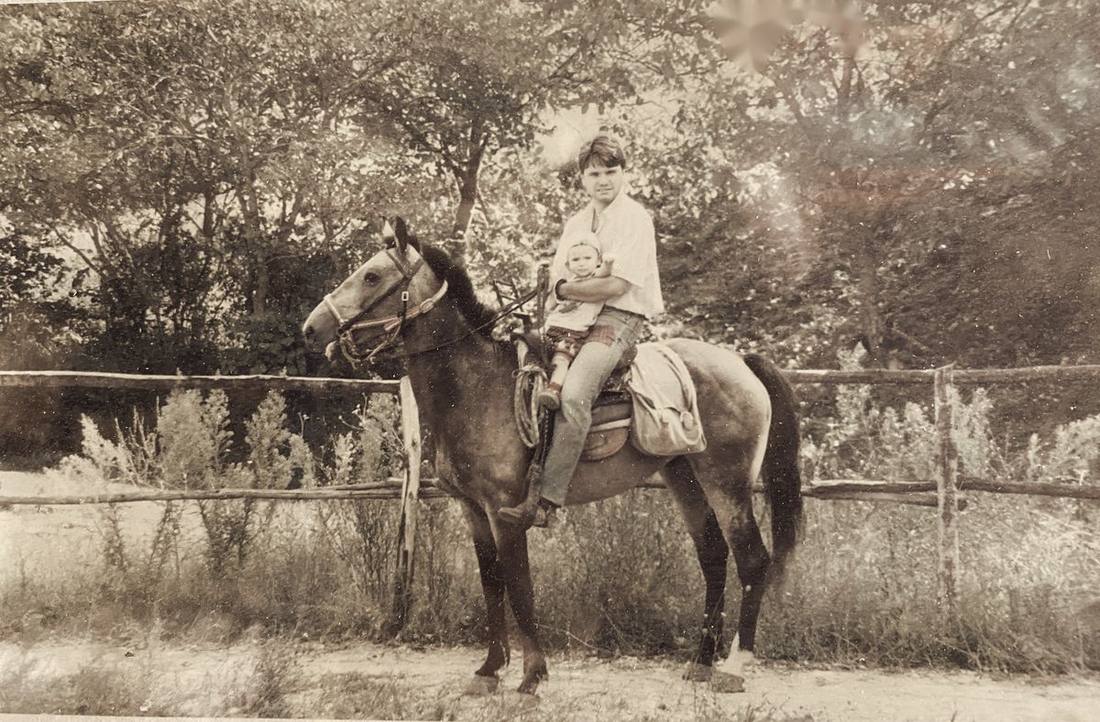 Lorenzo de bebé, a caballo delante de su padre junto a una cerca de madera
